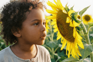 Criança explorando a natureza ao ar livre, representando o método de Pestalozzi que une Mente, Coração e Mão na educação infantil.